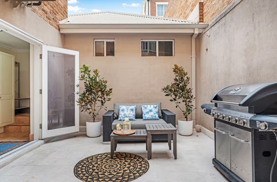Clean outdoor patio with seating area and barbecue grill